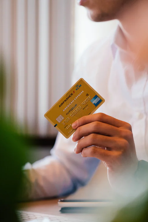 Mann in einem weißen Hemd hält eine goldene Kreditkarte in der Hand