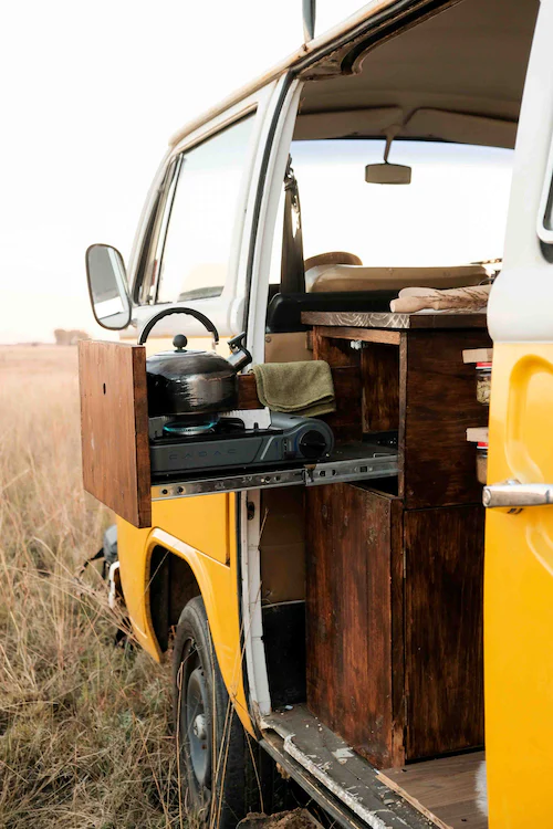 Gelber Van. Darin befindet sich ein kleiner geöffneter Schrank, in dem sich ein Teekessel auf einer Gasplatte befindet-